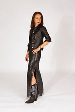 Woman wearing a black leather jacket, black sequin dress, evening wear, and black western boots