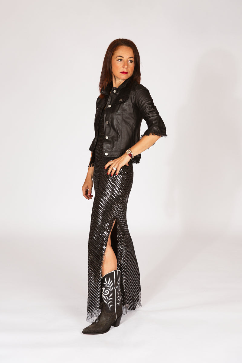 Woman wearing a black leather jacket, black sequin dress, evening wear, and black western boots