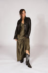 Woman wearing a black leather jacket, green dress, and black western boots-RockiesRebels collection