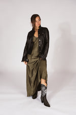Woman wearing a black leather jacket, green dress, and black western boots-RockiesRebels collection