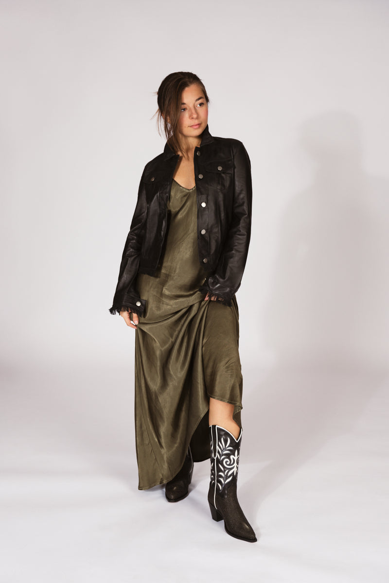 Woman wearing a black leather jacket, green dress, and black western boots-RockiesRebels collection
